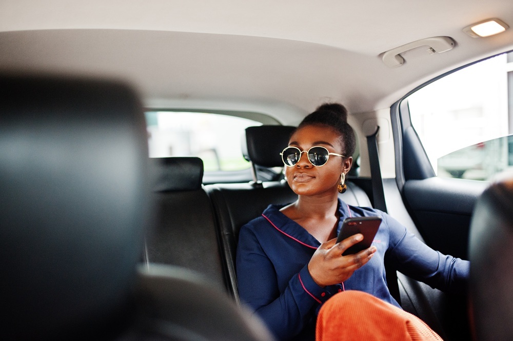 rich business african woman sunglasses sit suv car with black leather seats mobile phone hand 1.jpg